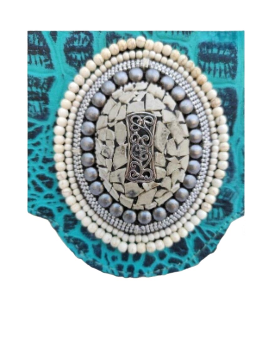 Bolso de piel de potro con solapa azul turquesa. Rodeado de piedras naturales turquesas blancas